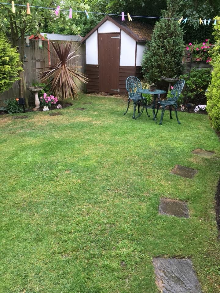 A cut lawn with stepping stones, planted edges and a garden table.