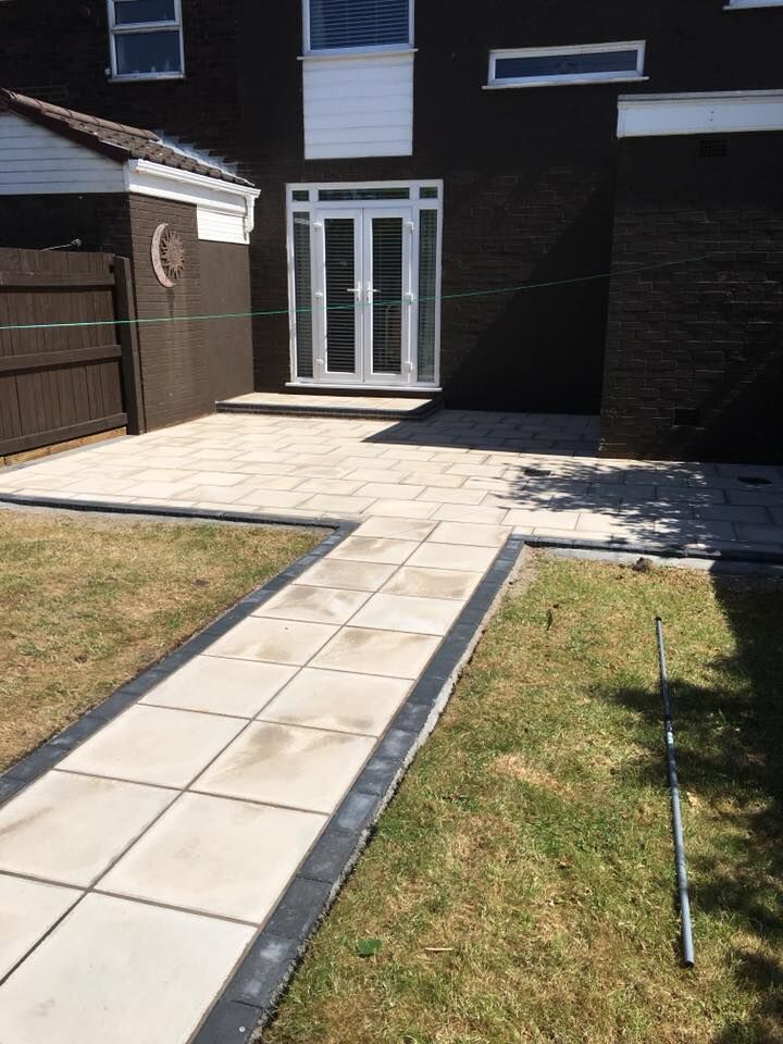 A paved path and step leading to patio doors at the back of a house.